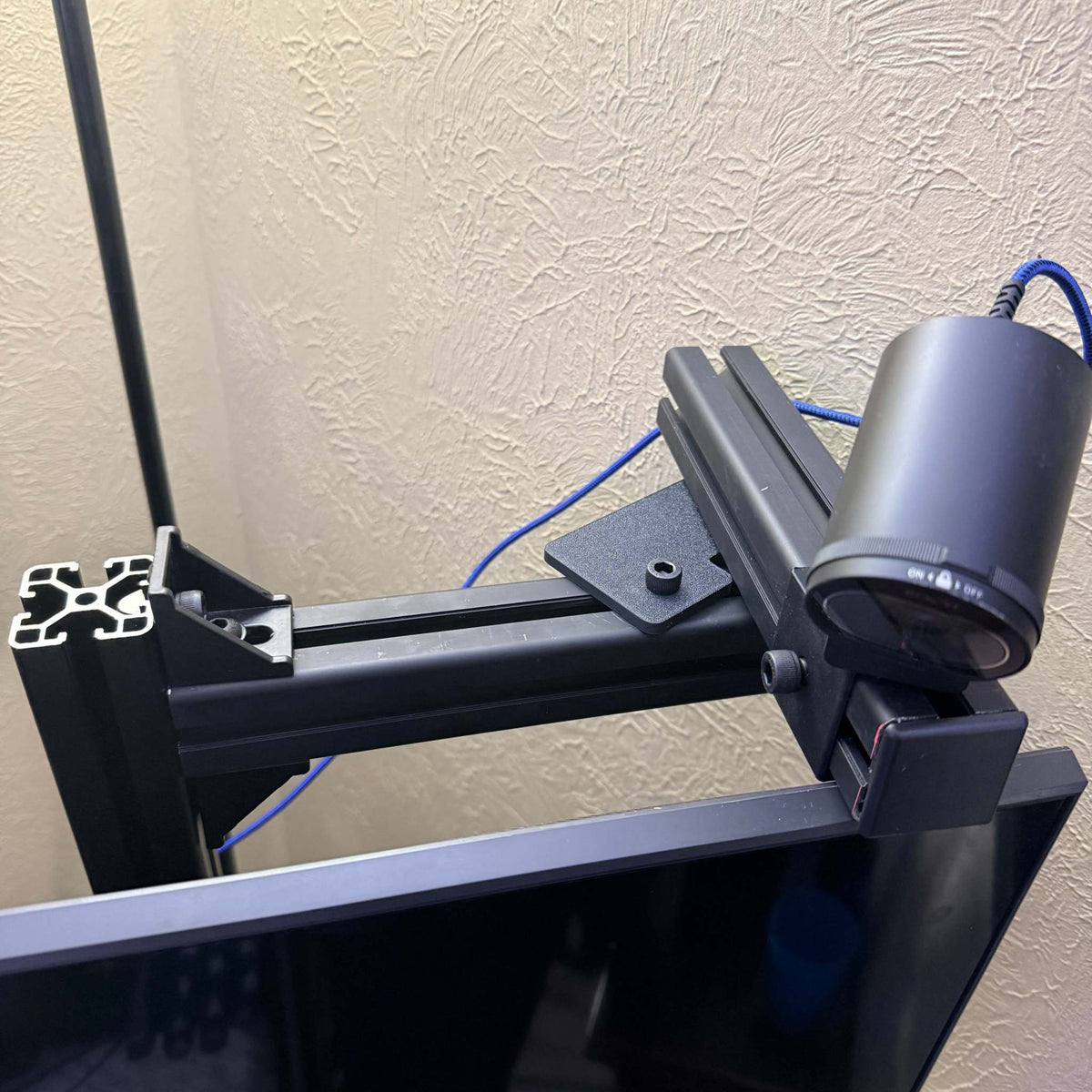 Sim Racing Rig camera mount made of black 4040 aluminum extrusion with adjustable arms and a mounted cylindrical camera.